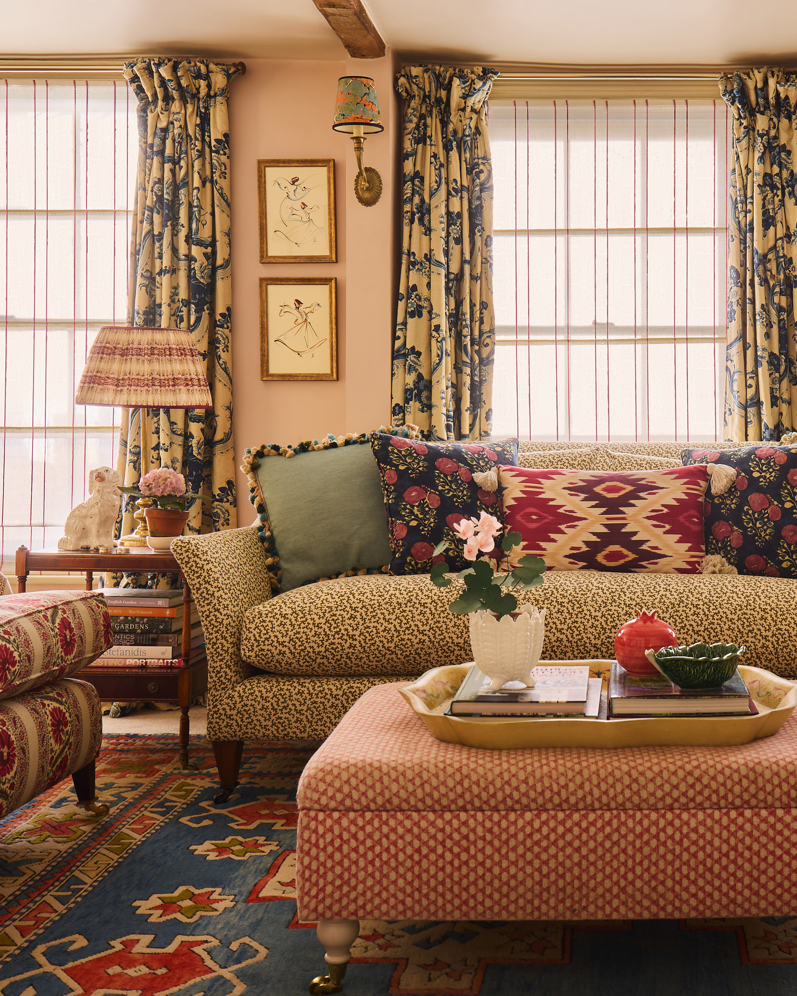Cosy sitting room with patterned sofa, kilim rug, patterned curtains, framed artwork and patterned cushions in a country cottage