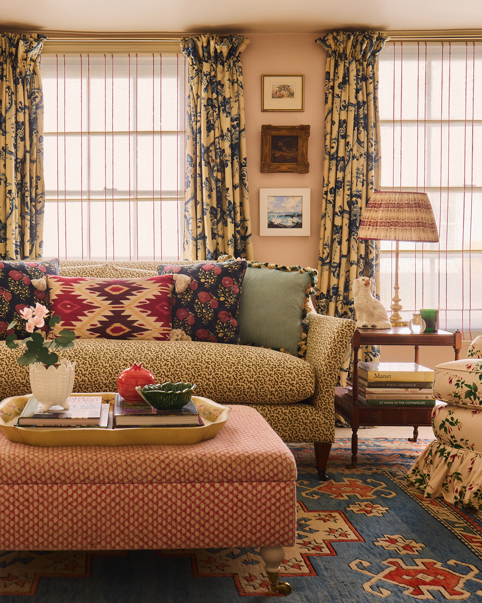 Close-up of sitting room with red patterned ottoman, patterned cushions, kilim rug and floral curtains in a Hampshire cottage